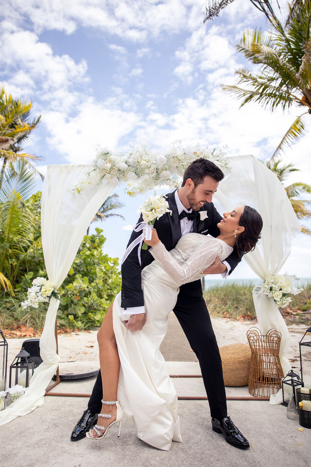 Couple sharing a romantic dip kiss under the ceremony arch